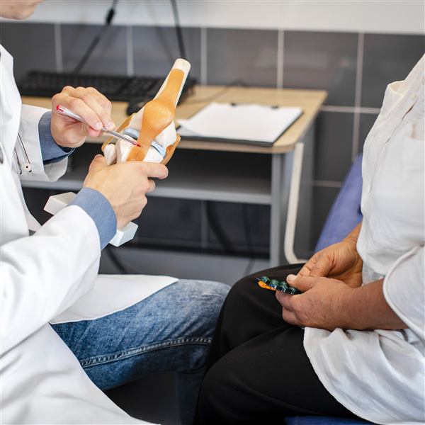 Médico señalando un modelo anatómico de la articulación de la rodilla